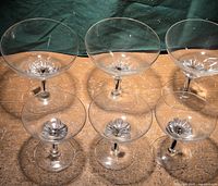 Six Balfour sherbert and champagne glasses shown from above on a surface, highlighting the black flower design at the bottom of each glass bowl.