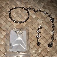 Overview photo showing the twisted silver bracelet alongside a small single hoop earring and a set of ear loops in a plastic bag.
