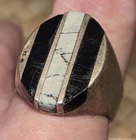 Top close-up of silver ring with black and white striped stone inlay showing surface detail and stone pattern.