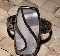 Top view of silver ring showing rectangular face with white and cream mother of pearl inlay