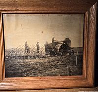 Framed antique black and white photograph circa 1918 showing a tractor and three men farming in a field.