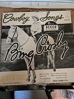 Black and white photo of Bing Crosby on white horse on 45 RPM record sleeve for Cowboy Songs by Decca Records