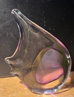 Side view of a clear blown glass fish sculpture with internal purple and yellow hues.