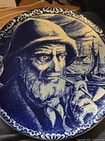 Close-up of Boch Delfts Blue plate showing detailed sailor portrait with pipe and marine background