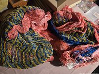 Photo of two tightly packed, multi-colored Guatemalan hammocks made of woven yarn with visible pink, blue, yellow, and white sections.