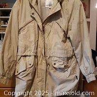 Front view of beige London Fog women's coat showing zipped chest and flap front pockets, elastic cuffs, and button snap closure.