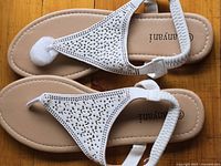 Top view showing the pair of white vegan sandals with perforated upper and ankle straps.