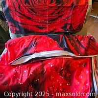 Red rose duvet cover partially unzipped showing the inside and matching pillowcase behind it on a couch.