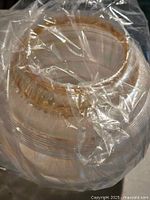 Two vintage clear glass globe light fixture covers wrapped in protective plastic showing textured frosted and ridged design with amber-tinted central openings.