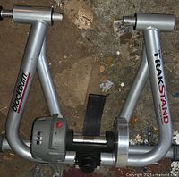 Overview of the Blackburn Trakstand stationary bike trainer frame on the floor, showing the silver frame with attached resistance unit and branding.