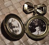 Open locket showing two black and white portraits inside: a child and a man.