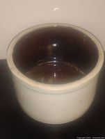 Top-down view of antique stoneware crock showing dark brown glazed interior and neutral exterior.