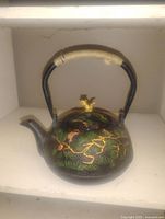 Cast iron tea pot with squirrel and pine branch design showing front angle and wrapped handle