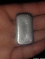 Metallic rectangular pewter ingot bar held in hand showing size and shape.