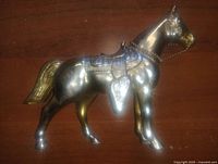 Side view of plated cast metal horse figurine showing detailed saddle and chain bridle