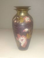 Small dark enameled brass urn vase with floral decoration, standing upright on flat surface.