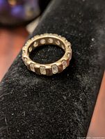Silver-tone costume cocktail ring placed on black fabric surface showing front view with rhinestone accents on vertical bars