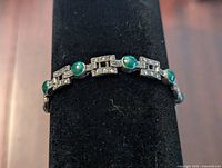Front view of silver bracelet showing oval green stones and geometric silver links with embedded stones.