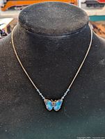 Front view of the blue butterfly pendant choker necklace displayed on a black bust.
