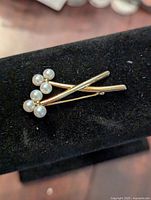 Image showing the front view of the gold-toned brooch with pearls arranged in small clusters on crossed stems.