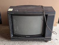 Front view of Sony Trinitron CRT TV showing screen, speakers, control buttons, and logo, with dust and wear signs.