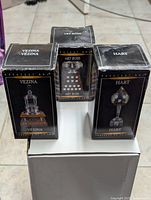 Front view of three boxed hockey trophy replicas: Vezina, Art Ross, Hart, arranged on a white surface.
