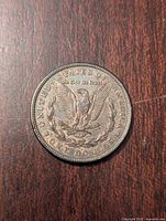 Reverse side of the 1921 Morgan Silver Dollar showing an eagle with outstretched wings clutching arrows and olive branch, surrounded by inscriptions.