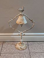 Full front view of vintage cast iron rooster bell showing the distressed white paint and rust.