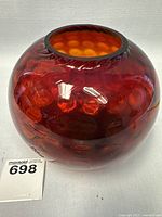 Full view of deep red rounded glass vase showing dimpled texture and top opening.