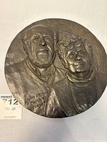 Top-level view of round bronze relief plaque featuring a couple, showing full portrait with inscription.