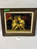 Full view of framed oil painting showing two cherubs reading a book with ornate wood frame and fabric liner.