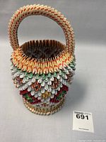 Front view of the colorful handmade origami paper basket with a sturdy handle and geometric patterns.