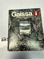 Original Iittala Gaissa box showing a single clear glass filled with liquid on textured background.