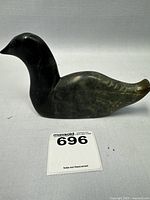 Side view of the dark greenish-gray soapstone goose sculpture with engraved wing details and a smooth finish.