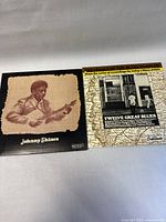 Both vinyl record covers side by side on a light surface showing album art and titles.