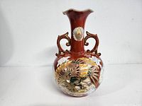 Front view of an old Chinese ceramic vase with reddish-brown body and detailed dragon and floral designs in relief.