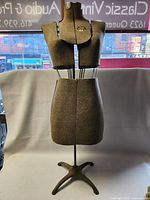 Front view of the vintage Acme adjustable dress form showing segmented torso sections covered in grey fabric with metal adjustment rods.