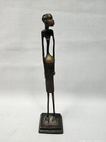 Front view of one vintage African tall brass woman figure on square base against white backdrop