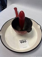 Photo of white interior 9-inch cast iron skillet with black chipped rim, holding the red egg poacher with removable handle inside