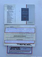 Photo showing several vehicle documents related to a 1997 Toyota Tercel, including owner's manual supplement, bill of sale, and pricing sheet.