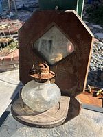 First photo showing antique wooden lamp holder with diamond-shaped mirror and a round glass oil lamp with rusted top sitting on a small wooden shelf attached to the backboard.