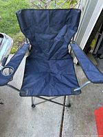 Blue foldable camping chair with metal frame, nylon seat and backrest, armrests including right side cup holder.