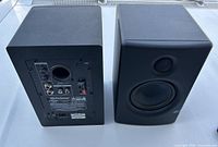 Two black PreSonus Eris E4.5 studio monitor speakers, front and back views showing speaker drivers and rear input/output connections.
