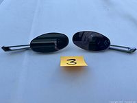 Pair of oval-shaped Harley-Davidson motorcycle mirrors with chrome stems and tinted glass placed on a white background.