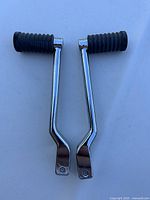 Pair of Harley Davidson stock shifter levers from Road King with ribbed black rubber foot pegs shown against white background.