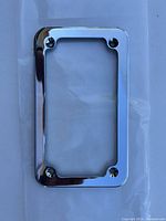 Clear image of a chrome motorcycle license plate frame with four mounting screws visible at each corner.