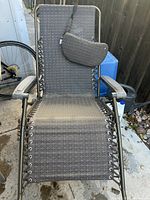 Weightless lounge chair in dark gray woven fabric with metal frame and adjustable reclining posture, including a separate headrest cushion.