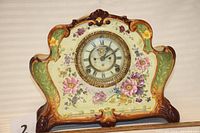 Front view showing the entire porcelain china clock case with hand painted floral decorations and brass bezel clock face.
