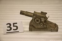 Front and side view of vintage die cast toy howitzer cannon showing its detailed mechanical design and silver paint wear.