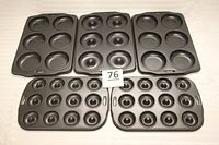 Five donut baking molds laid out on a table, showing the variety of sizes and hole patterns for different donut styles.